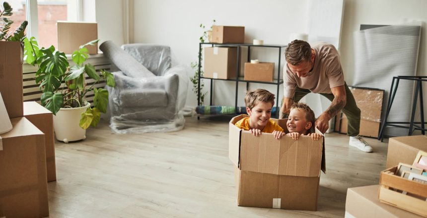 Man pushing around two children in a removals box and having fun